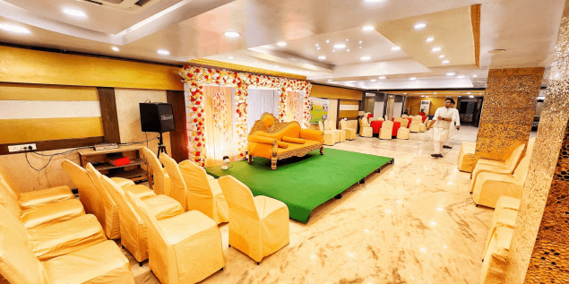 Wide-angle view of Mangalam Banquets AC hall and lawn area, showing elegant seating arrangements and green outdoor space.